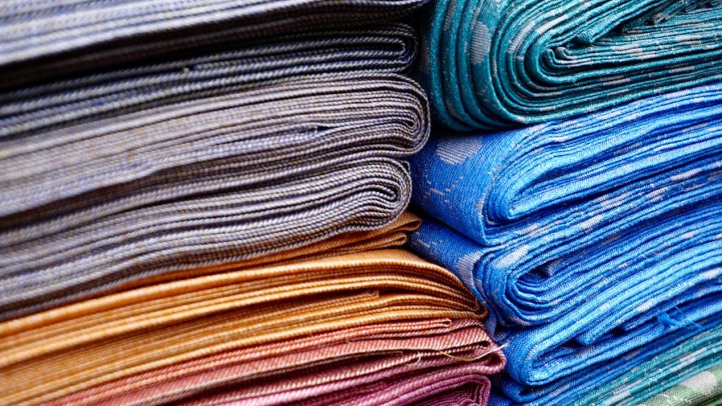Stacks of brightly colored printed quilting fabric in many patterns