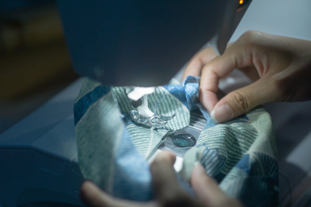 Hands guiding layered quilt fabric through a sewing machine