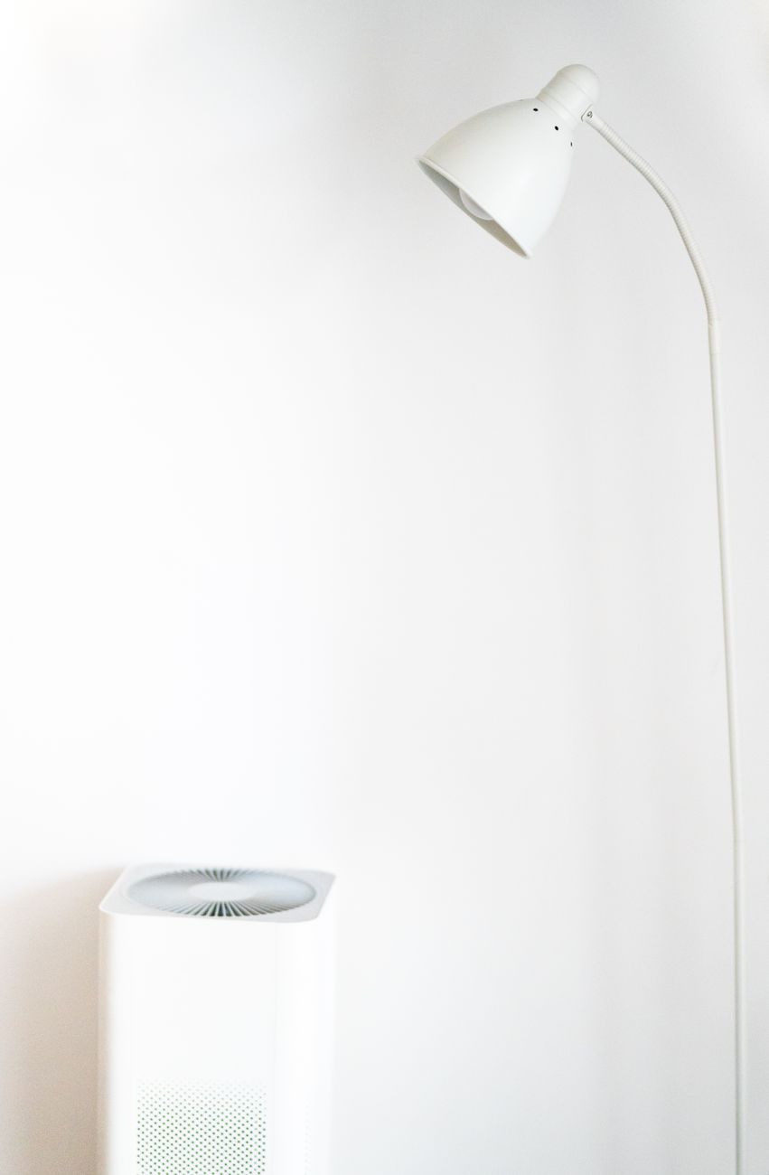 White air purifier running in a minimal white room to control litter box odor